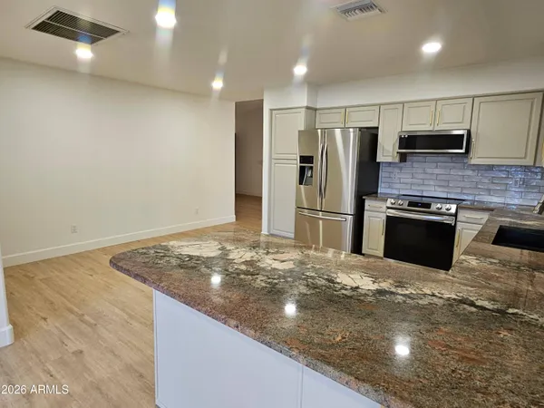 a kitchen with stainless steel appliances granite countertop a sink and a refrigerator
