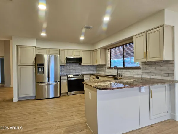 a kitchen with stainless steel appliances granite countertop a refrigerator a stove and a sink