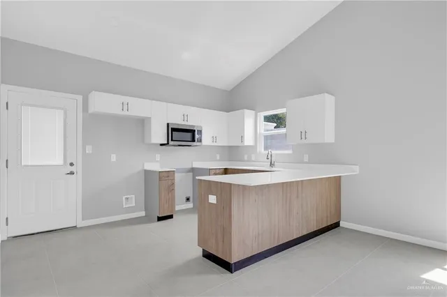 a large white kitchen with stainless steel appliances granite countertop a stove a sink dishwasher and a refrigerator with white cabinets