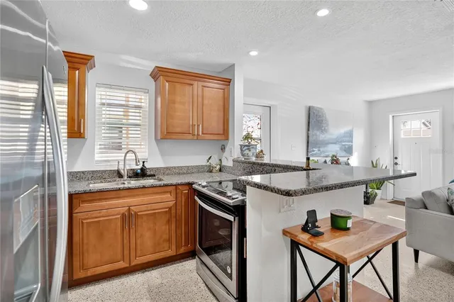 a kitchen with stainless steel appliances granite countertop living room and chairs