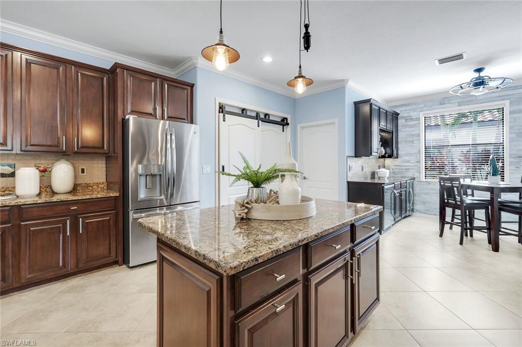 3783 Treasure Cove Circle Naples, FL 34114 - Photo 5 of 43 a kitchen with stainless steel appliances granite countertop a refrigerator a stove a microwave oven a sink a dining table and chairs