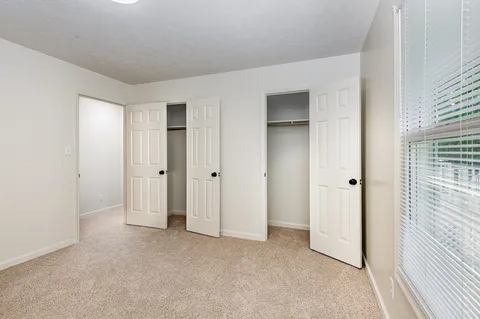 a view of an empty room with closet and a window
