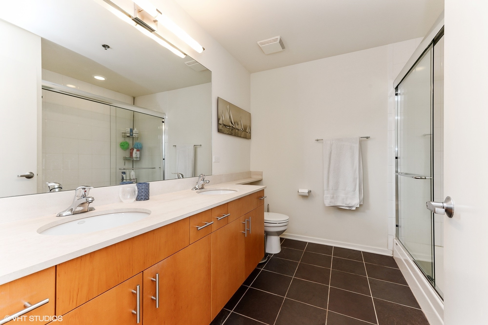 1040 West Adams Street, Unit 428 Chicago, IL 60607 - Photo 20 of 28 a spacious bathroom with a double vanity sink a mirror and a toilet