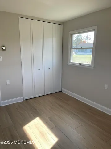 a view of an empty room with wooden floor and closet