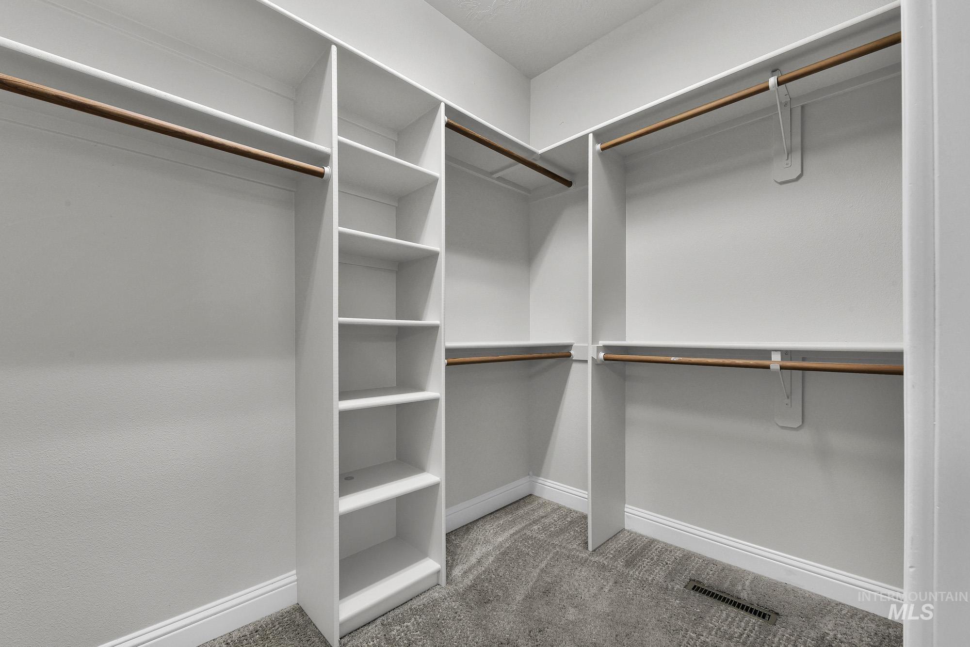 2172 West Cedar Grove Street Meridian, ID 83646 - Photo 19 of 49 Walk-in closet featuring built-in shelving, multiple hanging rods, white trim, and carpet flooring