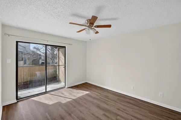 a view of empty room with wooden floor and ceiling fan