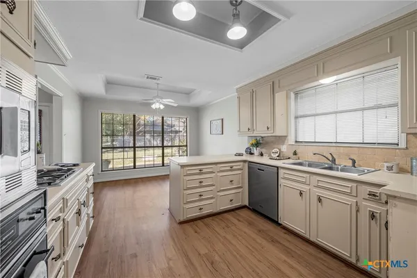 a kitchen with stainless steel appliances sink stove and wooden floor
