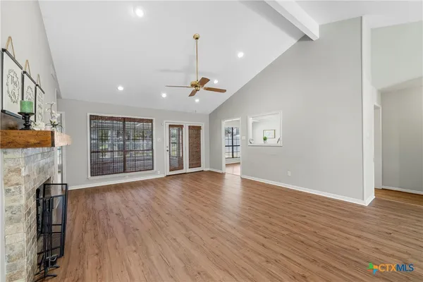 an empty room with wooden floor and windows
