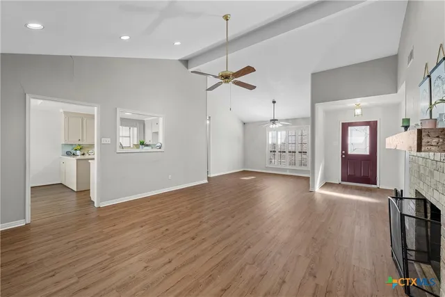 a view of an empty room with a window and wooden floor