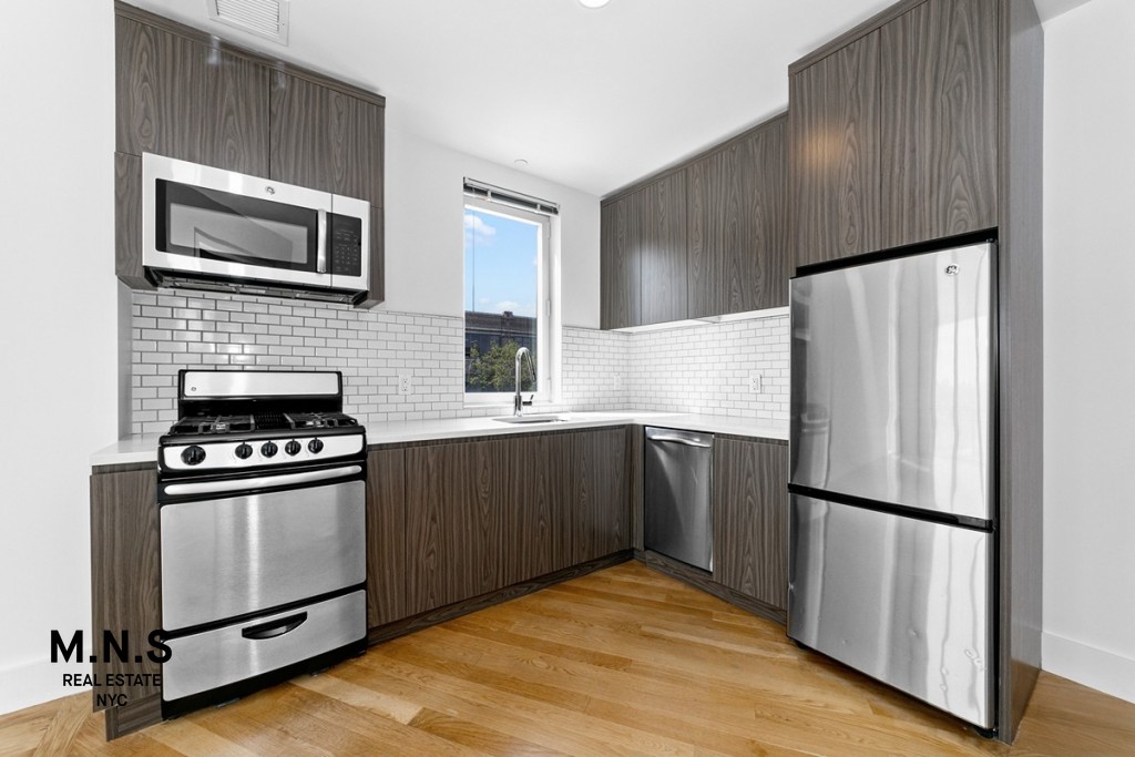 37-14 36th Street, Unit 7Q Queens, NY 11101 - Photo 3 of 20 a kitchen with granite countertop a refrigerator stove and microwave