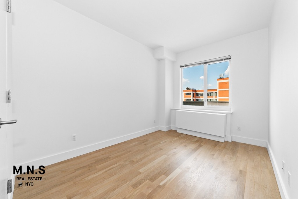 37-14 36th Street, Unit 7Q Queens, NY 11101 - Photo 7 of 20 an empty room with wooden floor and windows