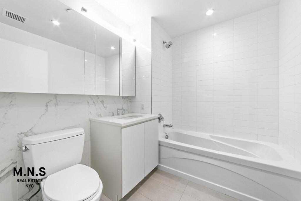 37-14 36th Street, Unit 7Q Queens, NY 11101 - Photo 8 of 20 a bathroom with a sink a toilet and a bathtub