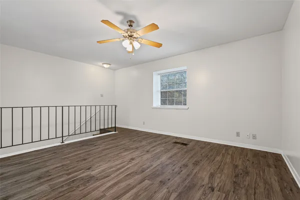 a view of an empty room with wooden floor and a chandelier