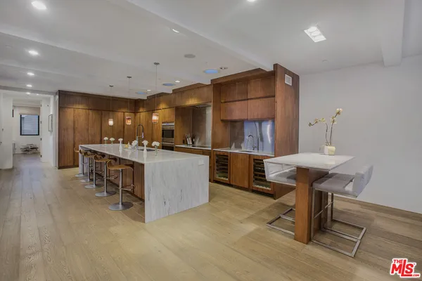 a kitchen with stainless steel appliances kitchen island granite countertop a table chairs sink and cabinets