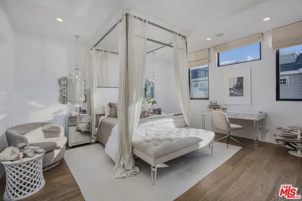 a bedroom with a bed a chandelier and mirror