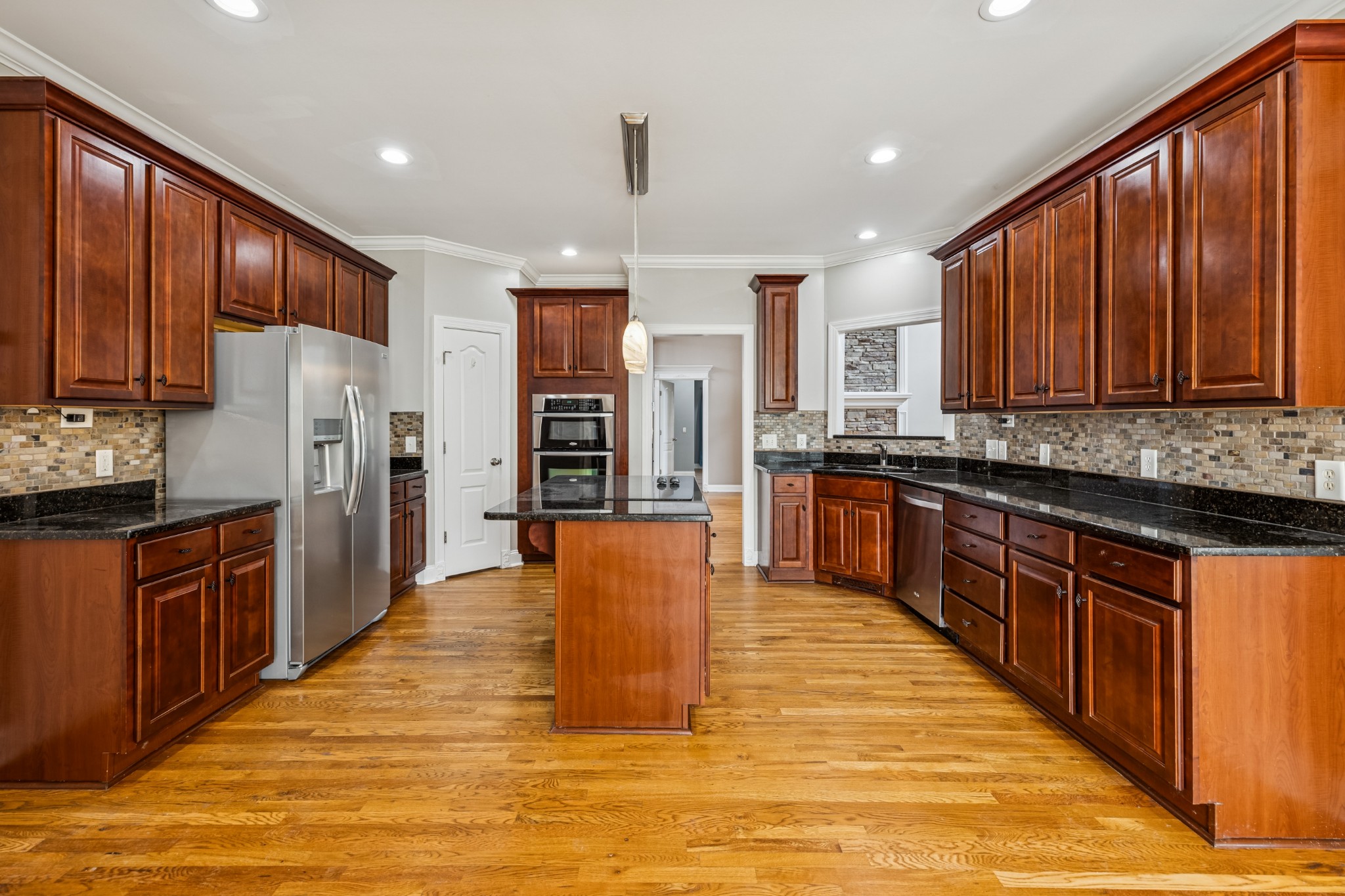 413 Stockbridge Way Mount Juliet, TN 37122 - Photo 25 of 49 a large kitchen with stainless steel appliances kitchen island granite countertop a stove a refrigerator a sink dishwasher and wooden cabinets with wooden floor