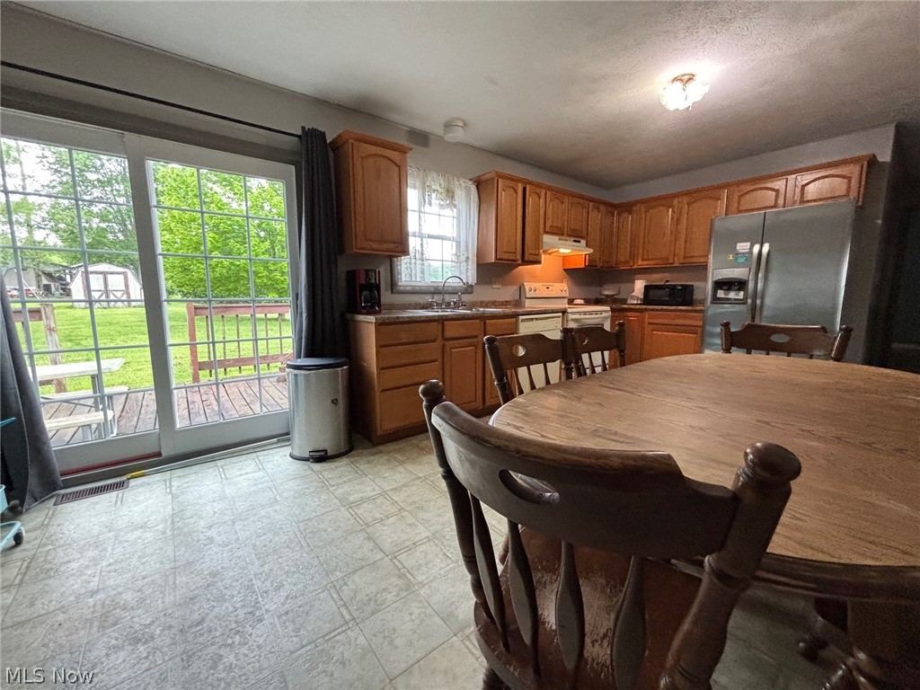 57575 Marietta Road Byesville, OH 43723 - Photo 6 of 25 Kitchen featuring wood-finish cabinetry, stainless steel refrigerator, white range, and a dual basin sink