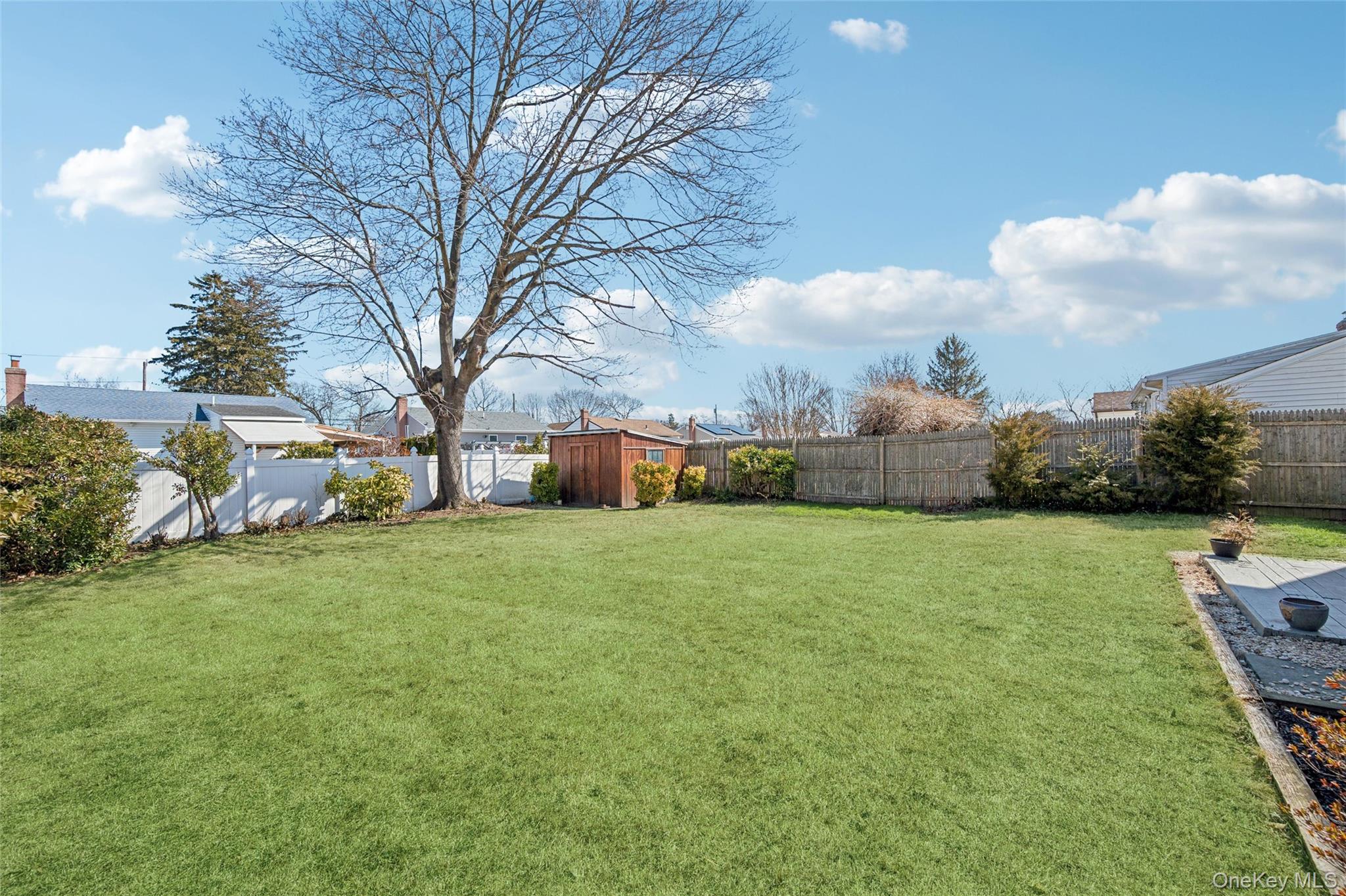 310 South 16th Street Lindenhurst, NY 11757 - Photo 18 of 23 a view of a big yard with potted plants and large trees