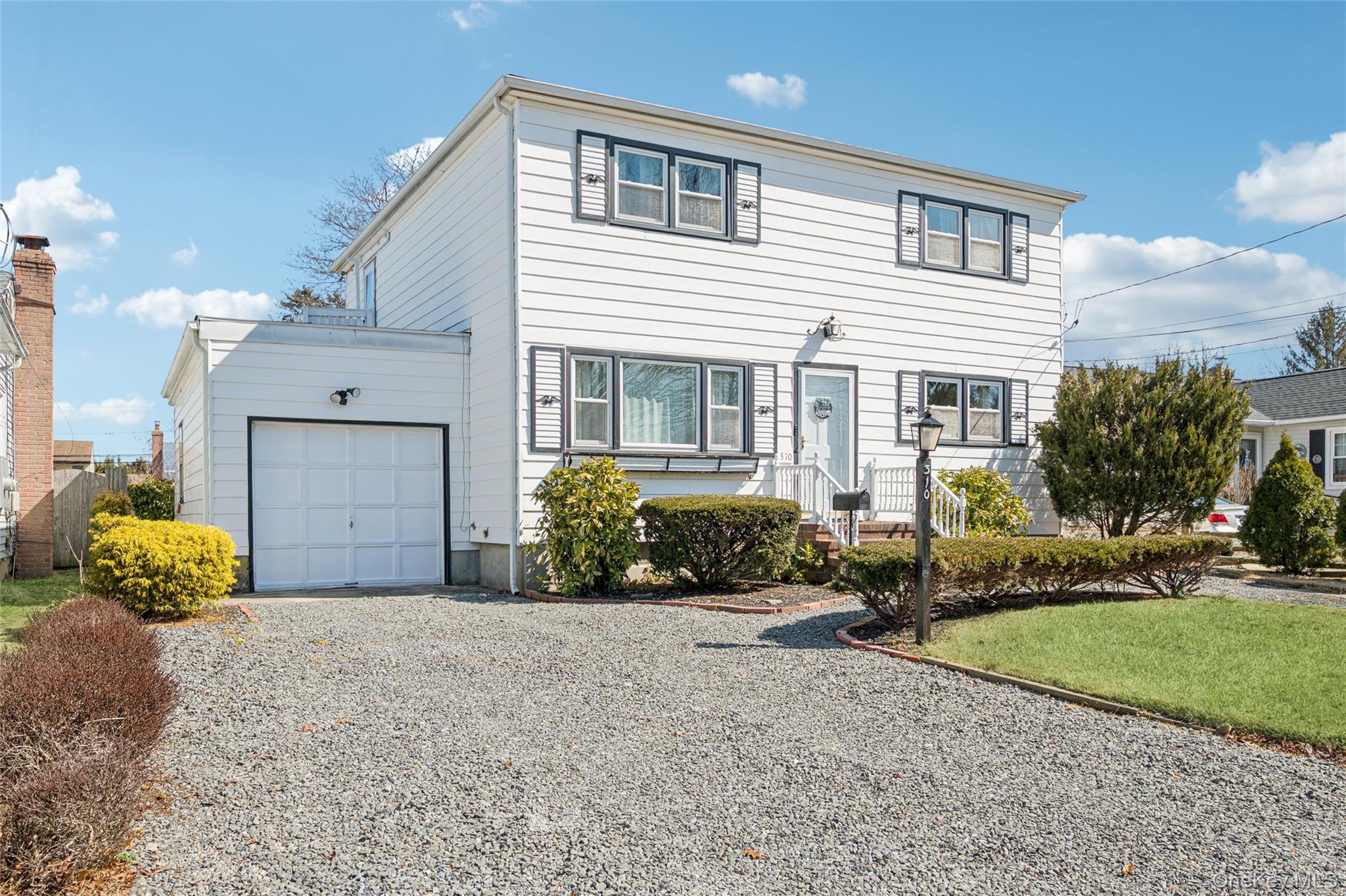 310 South 16th Street Lindenhurst, NY 11757 - Photo 2 of 23 a front view of a house with a yard and garage