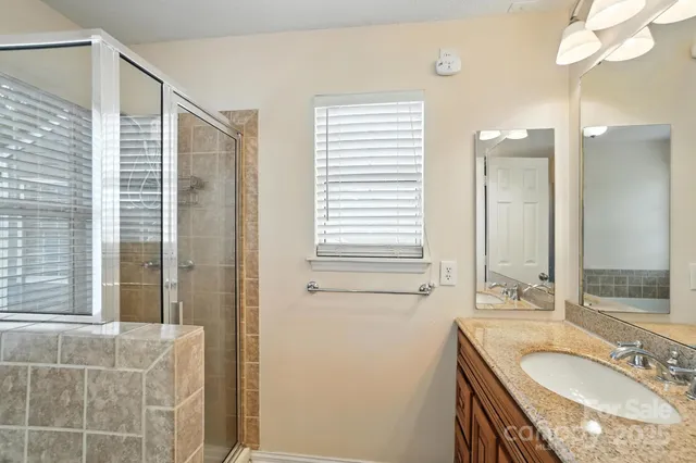 a bathroom with a granite countertop sink a mirror and a shower