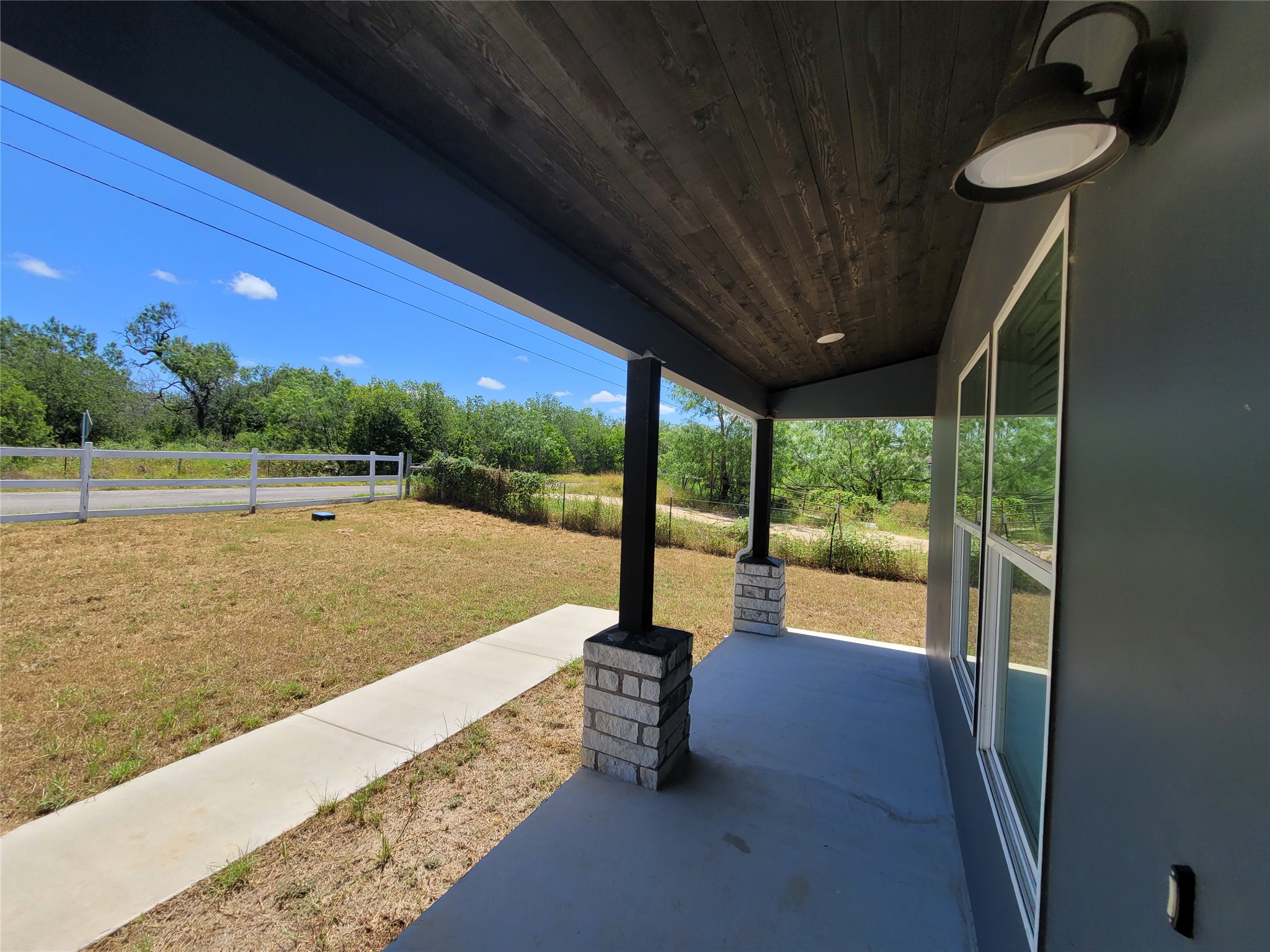 422 A Road Stockdale, TX 78160 - Photo 6 of 40 A welcoming front porch offers a peaceful view of the expansive, well-maintained yard.