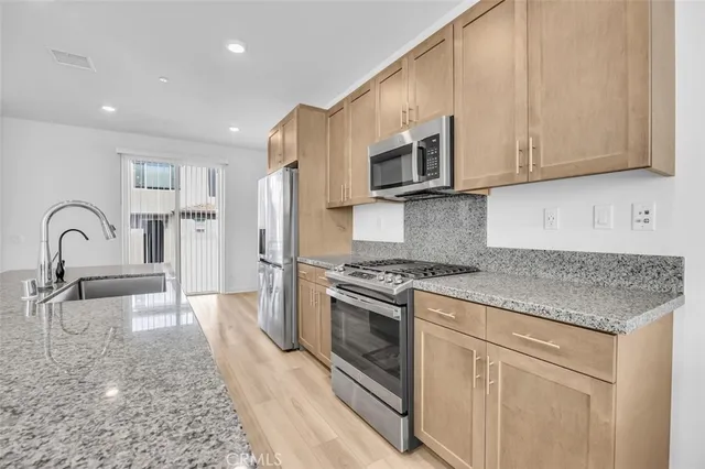 a kitchen with stainless steel appliances granite countertop a stove a sink and a microwave
