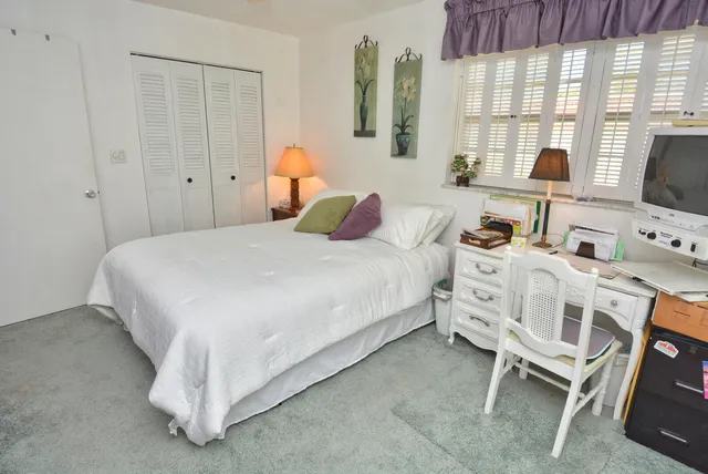 a bedroom with a bed and large mirror on the dresser