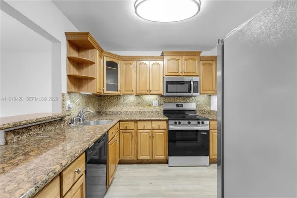 a kitchen with stainless steel appliances granite countertop a stove microwave and sink