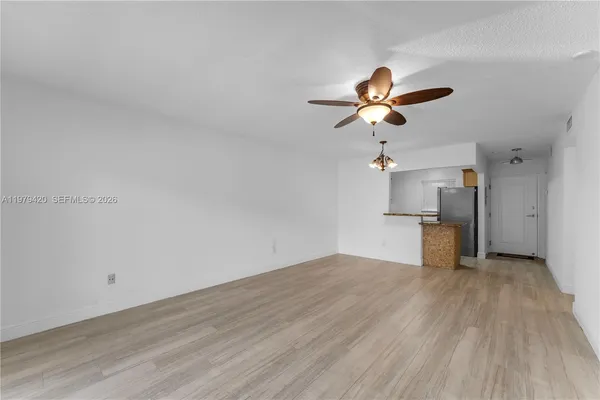 a view of a room with a kitchen and wooden floor