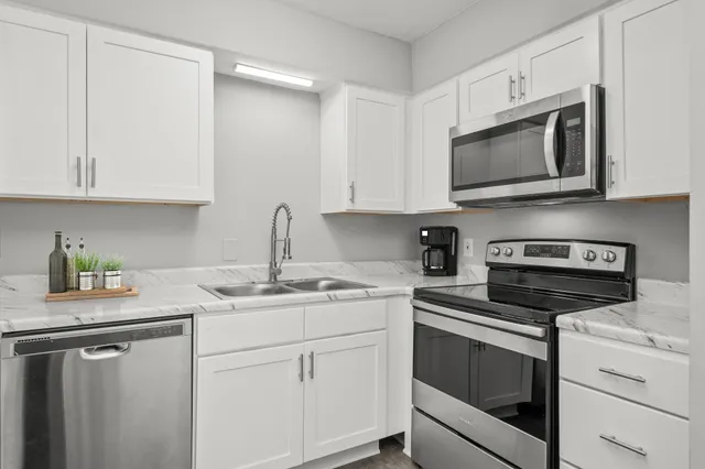a kitchen with white cabinets appliances and a sink
