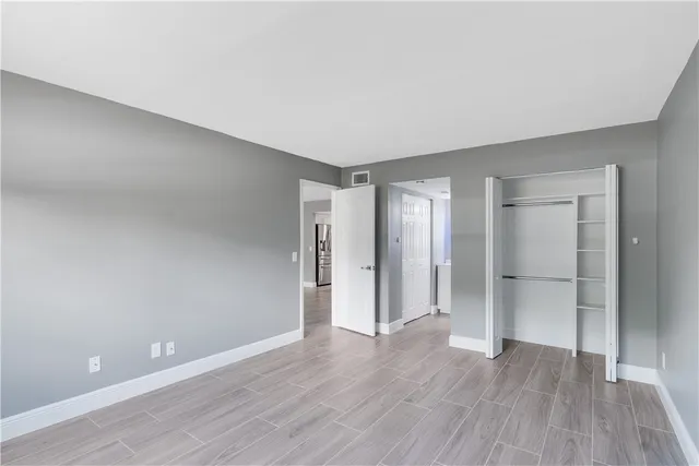 a view of an empty room with wooden floor and closet