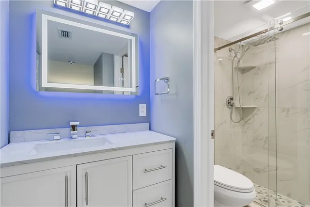 a bathroom with a granite countertop sink toilet and shower