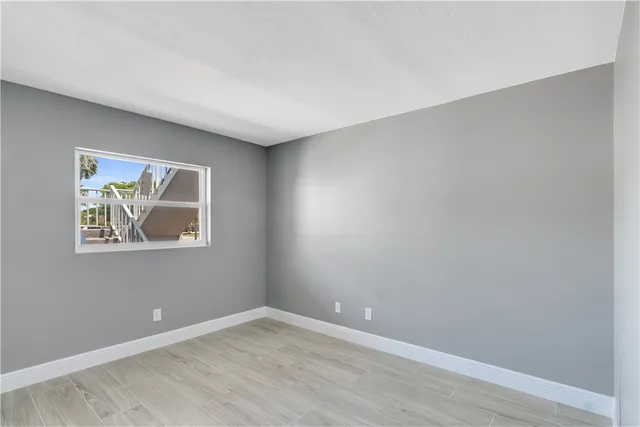 a view of an empty room with wooden floor and window