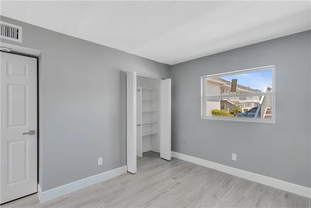 a view of an empty room with wooden floor and window