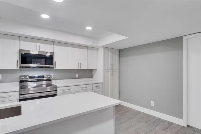 a kitchen with stainless steel appliances a microwave a stove and white cabinets