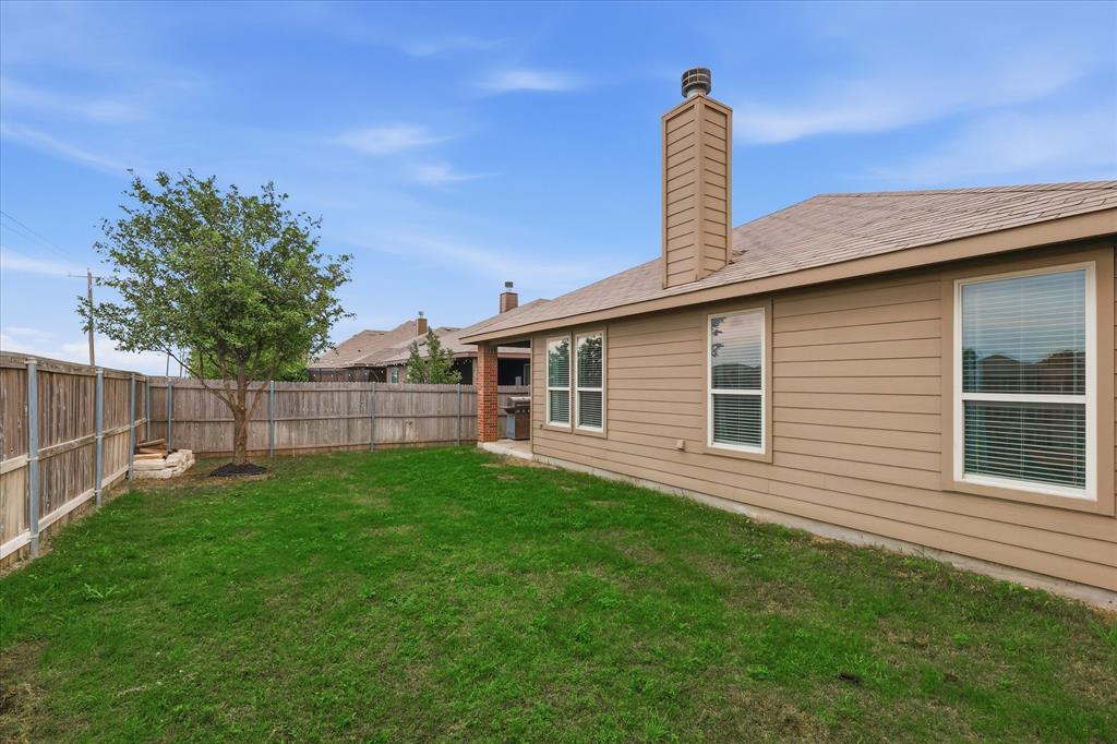 11500 Starlight Ranch Fort Worth, TX 76052 - Photo 34 of 40 The property features a spacious lawn, a mature tree, and a wooden privacy fence, providing a serene outdoor environment