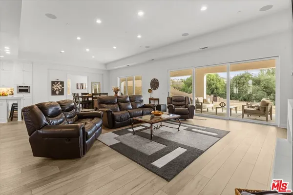 a living room with furniture large windows and wooden floor