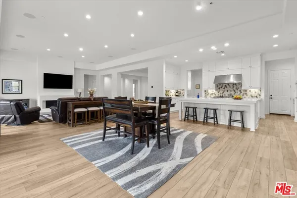 a living room with stainless steel appliances lots of furniture and wooden floor