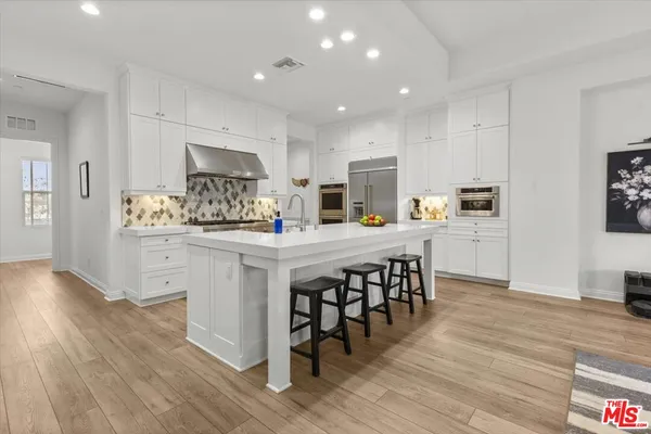 a kitchen with white cabinets and chairs