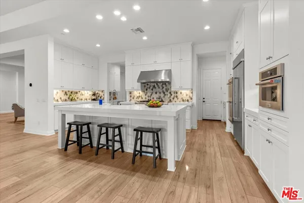 a kitchen with stainless steel appliances a dining table chairs stove refrigerator and cabinets