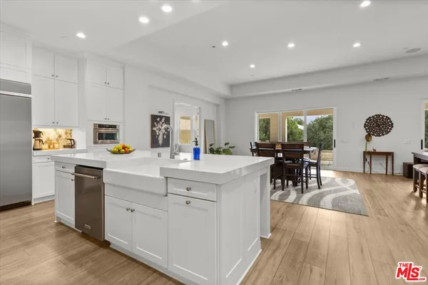 a kitchen with stainless steel appliances granite countertop a stove top oven a sink dishwasher and white cabinets with wooden floor