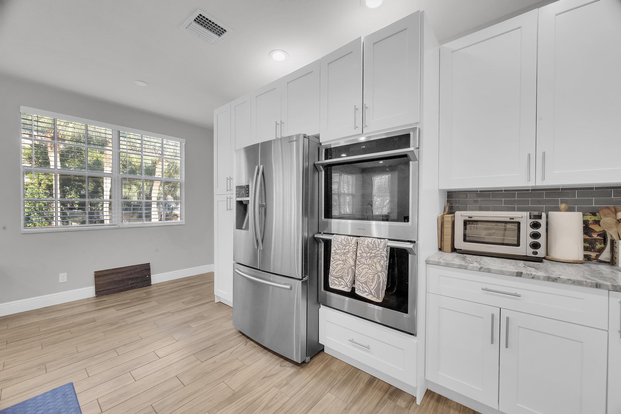 5600 Northeast Trieste Terrace Boca Raton, FL 33487 - Photo 23 of 44 a kitchen with granite countertop stainless steel appliances a refrigerator cabinets and wooden floor