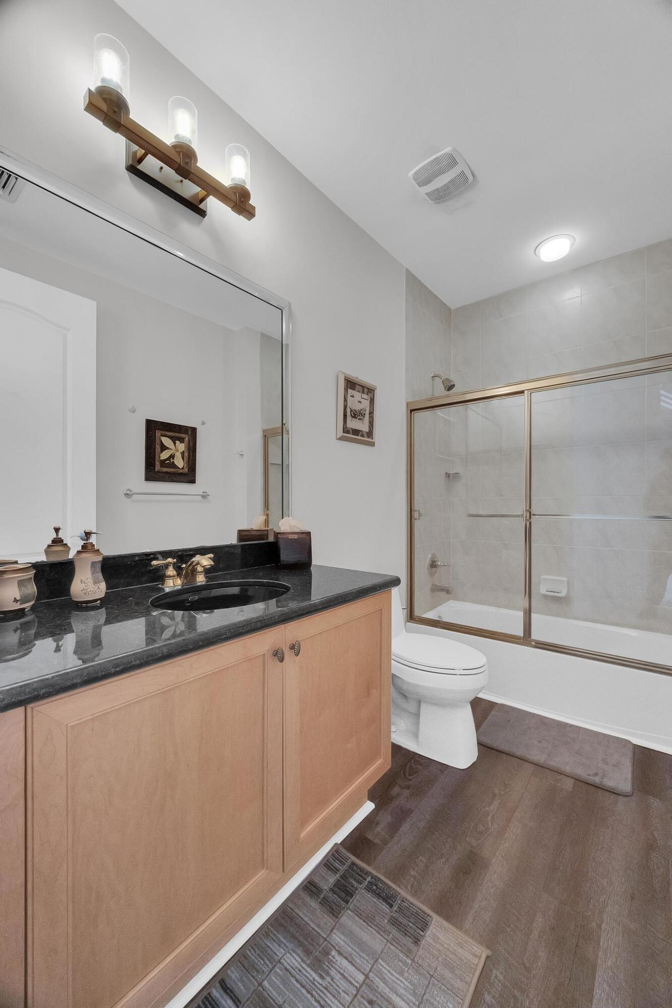 5600 Northeast Trieste Terrace Boca Raton, FL 33487 - Photo 33 of 44 a bathroom with a granite countertop sink a toilet a mirror and shower