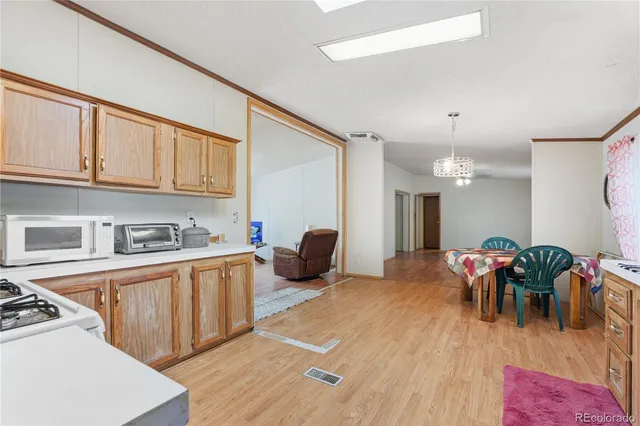 a kitchen with stainless steel appliances granite countertop a stove top oven a sink dishwasher and a dining table with wooden floor