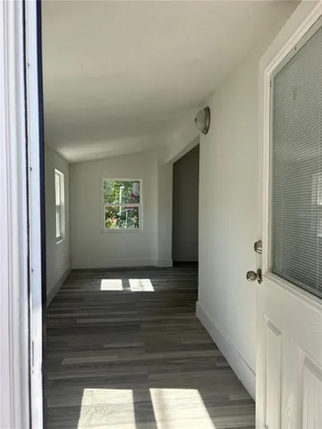 a hallway with wooden floor windows and entryway