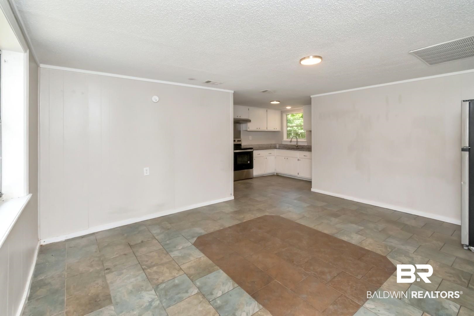 5650 Alice Drive Theodore, AL 36582 - Photo 3 of 15 Unfurnished living room featuring visible vents, baseboards, stone finish floor, a textured ceiling, and a sink