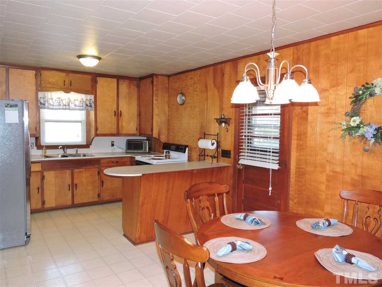 505 Robertson Road Roxboro, NC 27574 - Photo 3 of 16 a kitchen with stainless steel appliances granite countertop a sink a stove a dining table and chairs with wooden floor