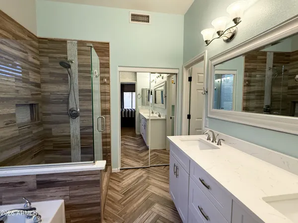 a spacious bathroom with a double vanity sink a mirror and shower
