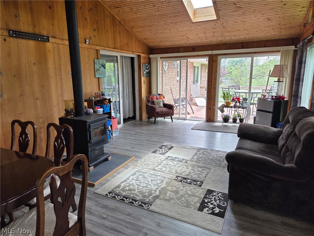 1761 May Road Mogadore, OH 44260 - Photo 26 of 46 Wood-paneled room featuring a black wood-burning stove with a hearth, multiple sliding glass doors, a skylight, and wood-finish flooring