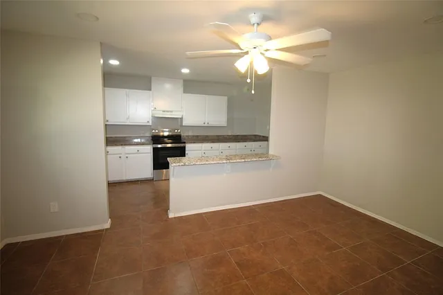 a view of kitchen with granite countertop cabinets and refrigerator